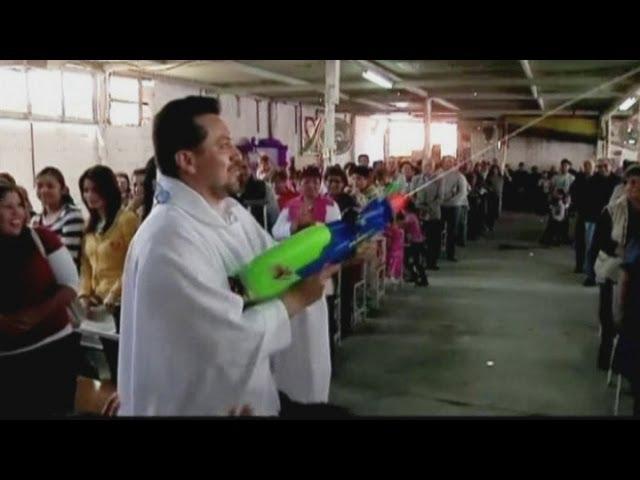Mexican priest uses watergun to spray holy water