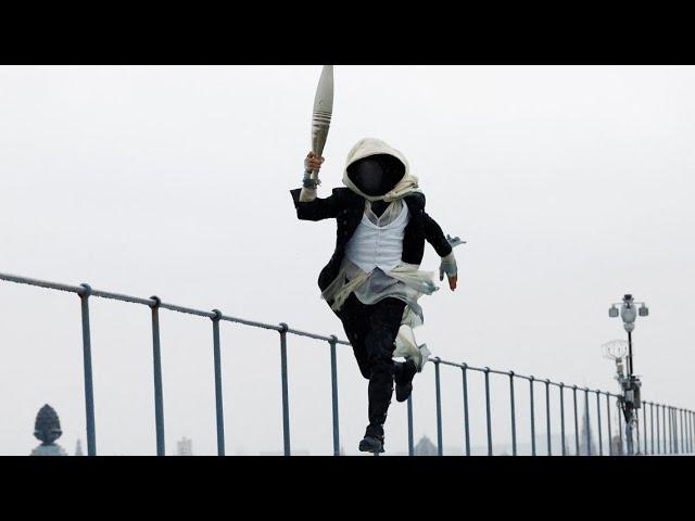 Who is the hooded character with the Olympic torch?