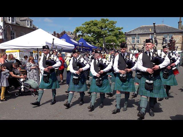 Dunnottar Pipes and Drums march through crowds during 2024 Stonehaven Feein market in Scotland