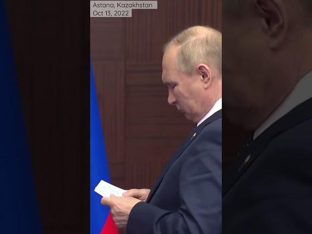 What is Putin reading when waiting for shaking hands with Turkey’s Erdogan