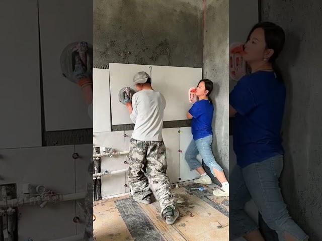 The process of laying wall tiles by a man and a woman
