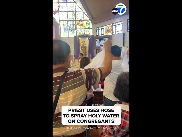 Priest uses hose to spray holy water on congregants