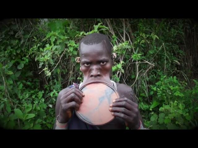 Surma tribe woman removing an putting her lip plate, Kibbish Ethiopia