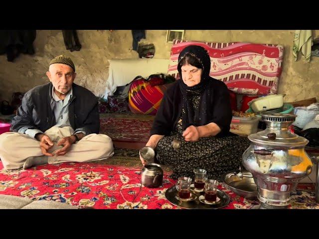 Village men and women in a traditional hut _  An old village woman cooks for her husband