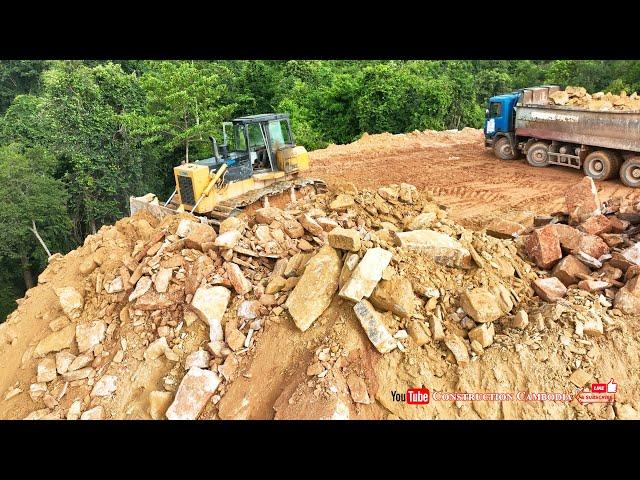 Technique dozer pushing rocks and dump trucks cleaning rocks on mountain building road construction