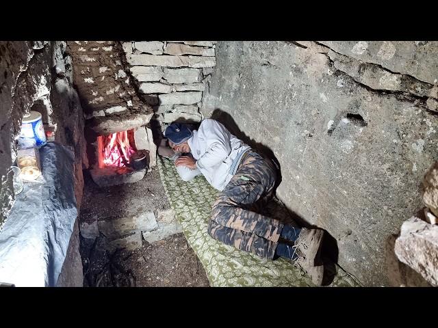 Building a warm and cozy shelter for survival in the rain between rocky cliffs in the mountains