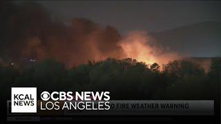 Firefighters work to put out Colton brushfire as winds hit the area