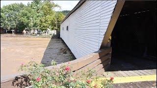 Crowd Gathers at Covered Bridge During Flood