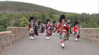 Drum Majors lead the Scottish Pipe Bands over river Dee marching to 2023 Ballater Games in Scotland