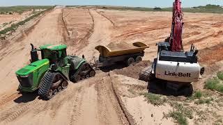 Link-Belt 490 x4 loading John Deere 9r 640 with side dump trailer.