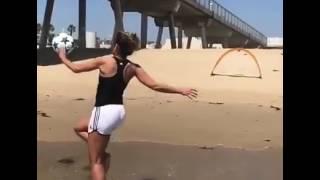 hermosa chica entrenando futbol en la playa