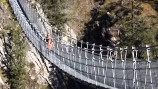 Scooter stuntman rides on the back wheel with a Wheely over largest suspension bridge in the world