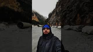 Man is standing on the foot of mountains and eating sausage taking selfie