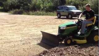 Deere D130 riding mower using Nordic Plow in summer