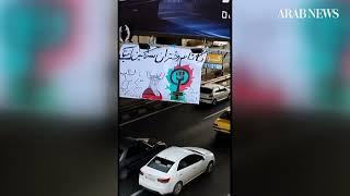 Woman in Iran hangs banner in Tehran bearing caricature of Ayatollah Khamenei