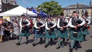 Dunnottar Pipes and Drums march through crowds during 2024 Stonehaven Feein market in Scotland