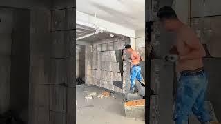 A worker removes cut concrete blocks from a wall