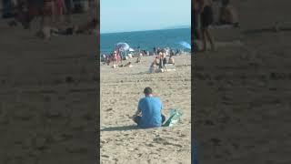 View of the Atlantic Ocean, blue sky, umbrellas and crowds of beachgoers