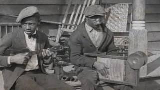 Street musicians Carl Scott and Eddie Thomas playing ukulele, kazoo, washboard, and a coffee pot.
