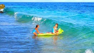 Children swim on a mattress in the sea 4K.