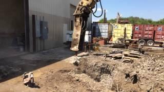 Using a hoe ram to break up 24" thick concrete slab for electrical conduits.