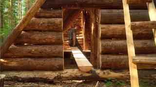 A MAN BUILDS A LARGE LOG CABIN ALONE. THE FLOOR IS MADE OF PINE BOARDS.