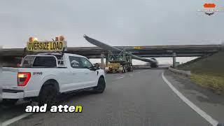 Oversized truck hauling wind turbine blade under a bridge - Skilled Driver