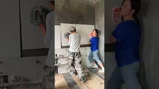 The process of laying wall tiles by a man and a woman