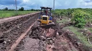 Powerful dozer pushing clearing mud soil before backfilling work with red soil.