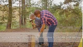 Side view of father teaching son chopping firewood with axe