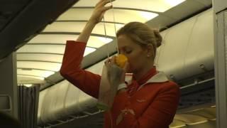 Aeroflot stewardess. Lady in exciting red dress explains emergency procedures.