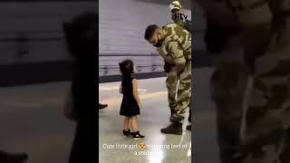 Cute little girl  touching feet of a soldier