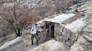 Building a warm and cozy shelter for survival in the rain between rocky cliffs in the mountains